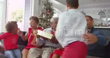 孩子们在家里给爷爷奶奶送圣诞礼物——他们摇着包裹，试着猜一猜里面是什么